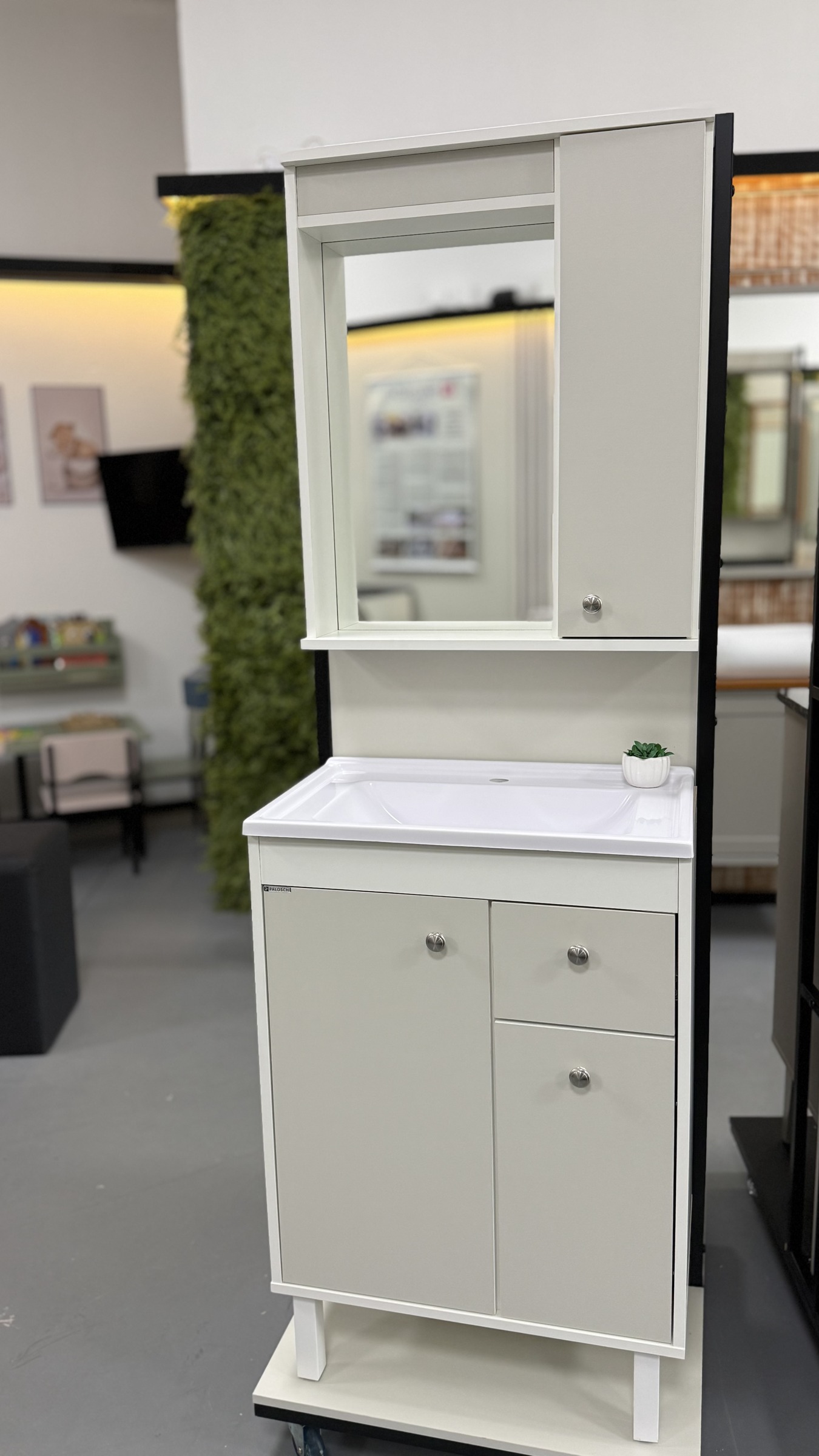 Fotografia real do Forli 60 cm claro com uma porta, duas gavetas, pés, tampo de marmorite branco e espelheira com porta lateral na loja; estrutura preta e base com rodízios somente de exposição