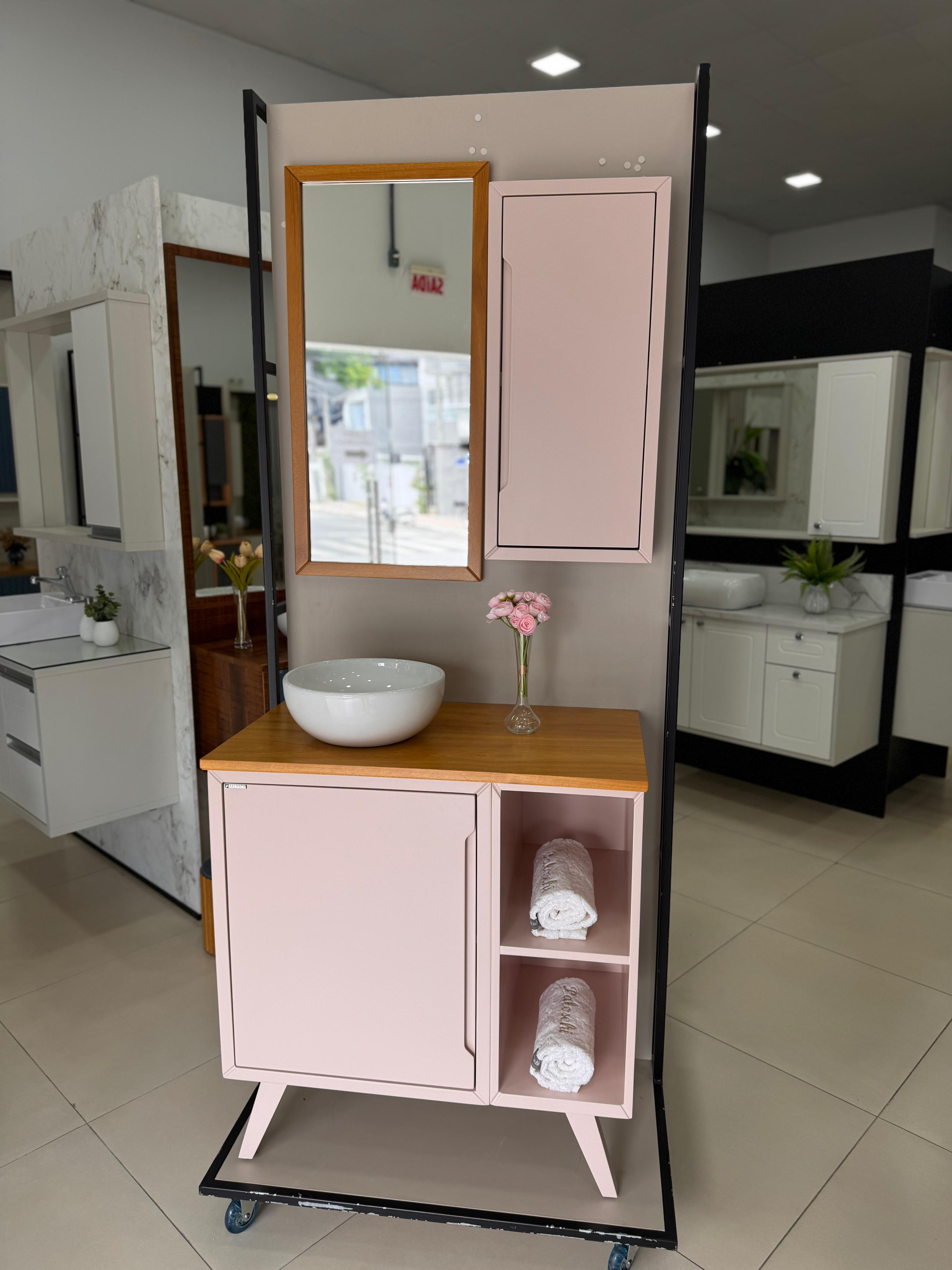 Fotografia real do Raffinati 75 cm rosa com pés, porta à esquerda, dois nichos à direita, tampo de madeira, cuba branca de apoio, espelho emoldurado em madeira e armário lateral rosa na loja